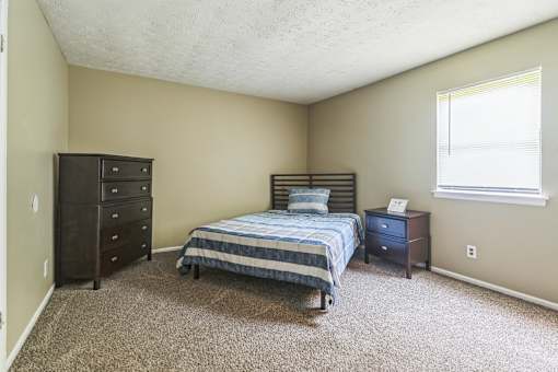 A bedroom with a bed, nightstand, and dresser.