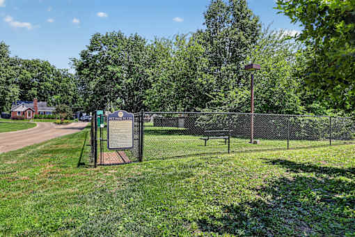 A sign is posted on a fence in a park.