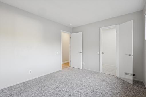 A room with a carpeted floor and three doors.