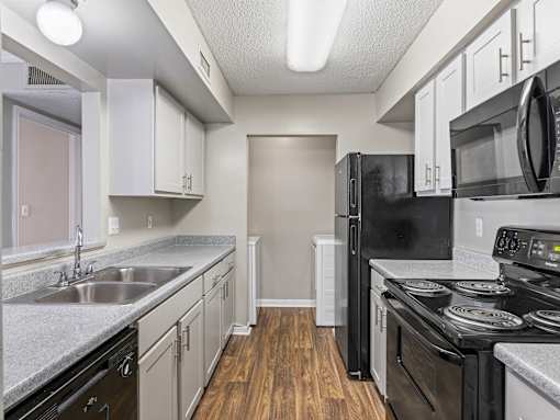 Kitchen with white cabinets and black appliances at Park at Meadow Ridge Montgomery AL
