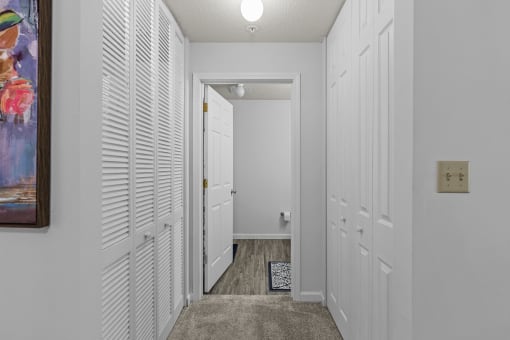 a hallway with white closet doors and a door to a bathroom