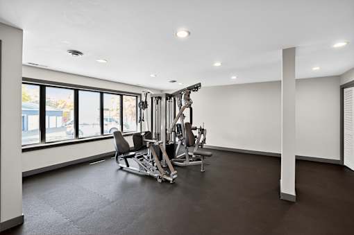 A gym with a rowing machine and a bench.