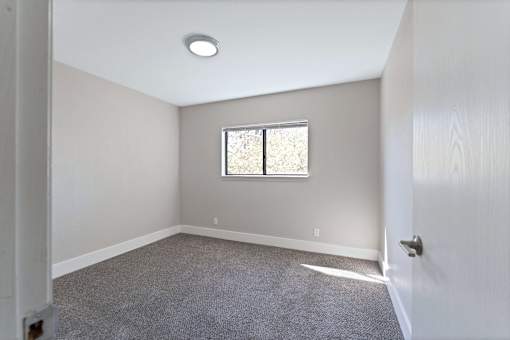 A room with a window and carpeted floor.