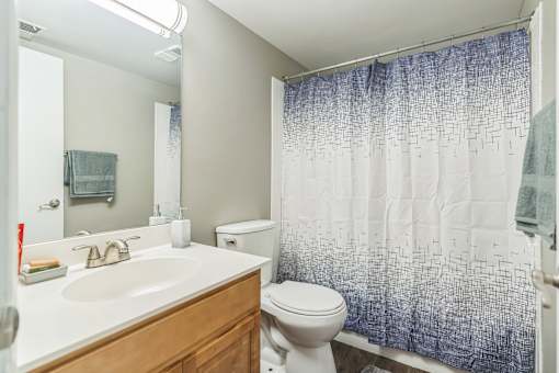 A bathroom with a white sink, toilet, and a blue shower curtain.