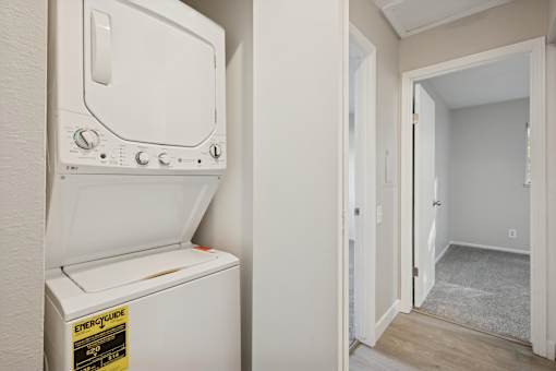 A white electric dryer is on the wall next to a door.