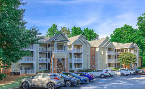 a row of apartment buildings with cars parked in a parking lot