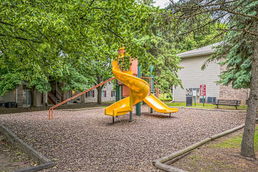 A playground with a yellow slide and a red climbing frame.