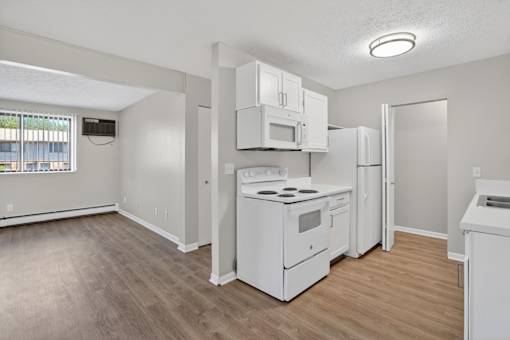 A white kitchen with wood flooring and white appliances.