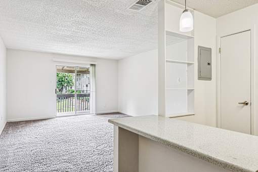 A white room with a carpeted floor and a door leading to a balcony.