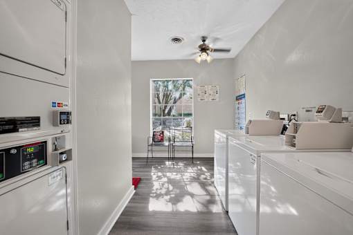 A white kitchen with a window and a ceiling fan.