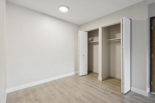 A room with a white wall and a brown floor with a white door.