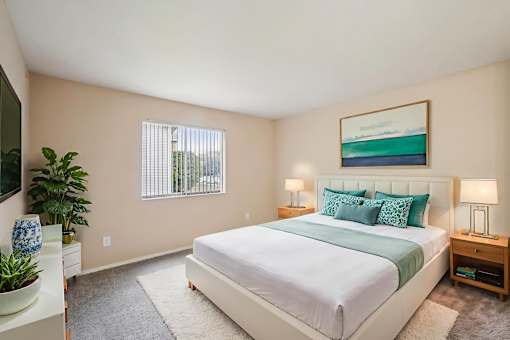 A bedroom with a large bed and a painting on the wall.