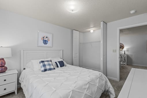 a bedroom with a white bed and a closet