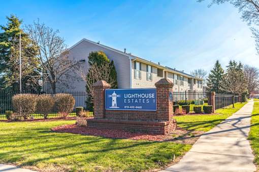 The image shows the entrance to Lighthouse Estates with a sign and a building in the background.