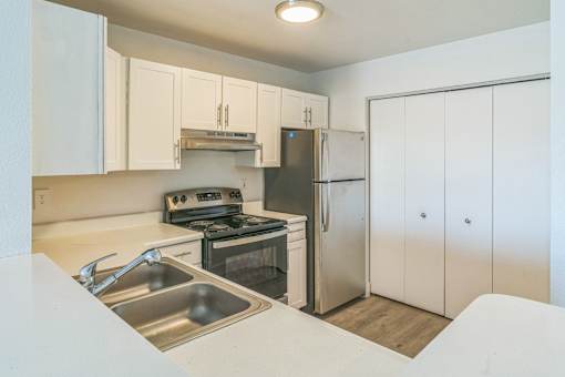 A kitchen with a stove, sink, and refrigerator.