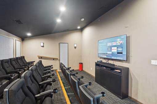 A row of black chairs are arranged in front of a television in a room.