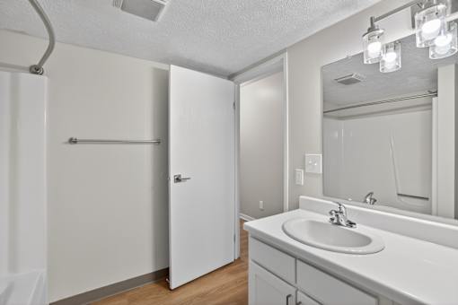A white bathroom with a sink, mirror, and shower.