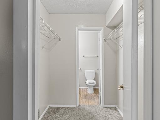 A white toilet is in a small bathroom with white walls and a white door.