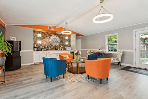 A modern kitchen with orange chairs and a wooden floor.