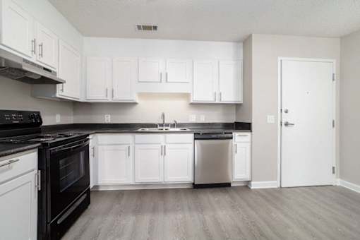A kitchen with white cabinets and black appliances.