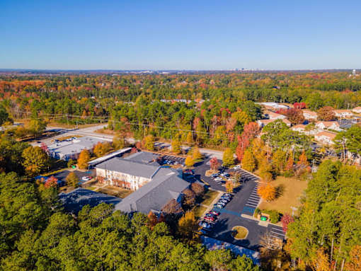 An aerial view of a parking lot and a building surrounded by trees.