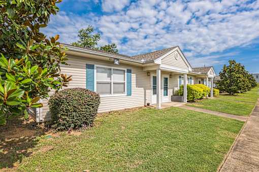 A house with a green lawn and a blue sky.