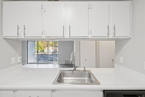 A kitchen with white cabinets and a stainless steel sink.