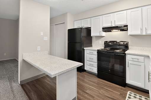 A kitchen with black appliances and white cabinets.