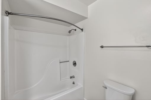 A white bathroom with a tub and toilet.