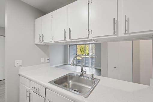 A kitchen with white cabinets and a stainless steel sink.