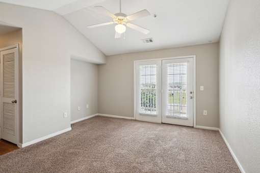 A room with a ceiling fan and carpeted floor.