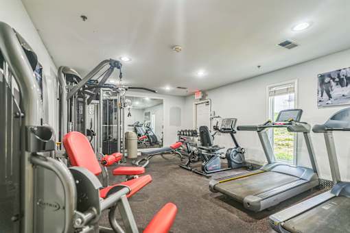 A gym with a variety of equipment including treadmills, weights, and exercise machines.