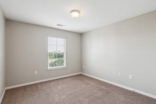 A room with a window and carpeted floor.