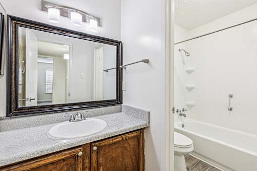 A bathroom with a white tub, sink, and mirror.
