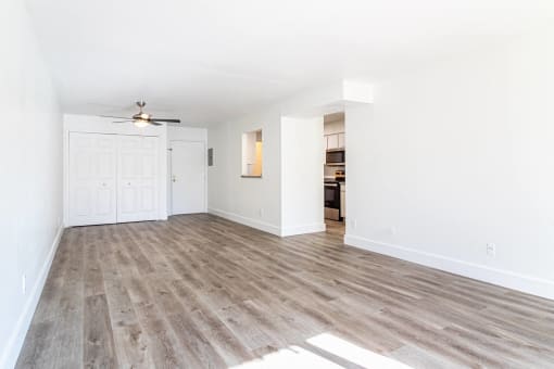 an empty living room with wood flooring and a ceiling fan