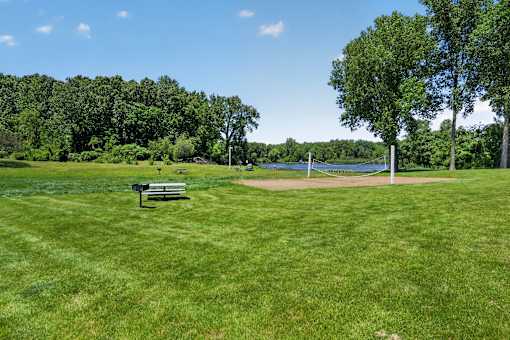 A park with a bench and a baseball field.