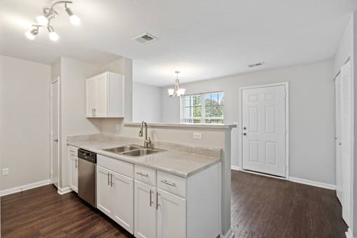 A kitchen with white cabinets and a wooden floor.