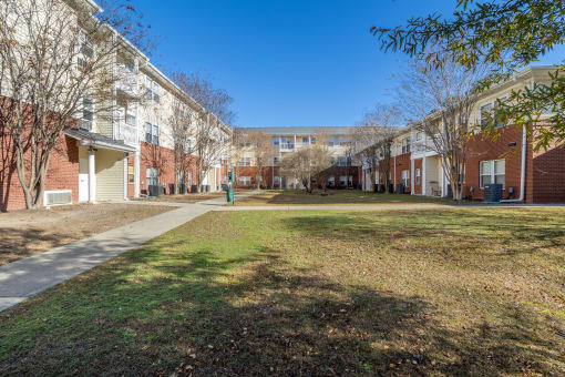a grassy area in front of a row of brick apartment buildings