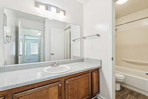 A bathroom with a sink, mirror, and bathtub.