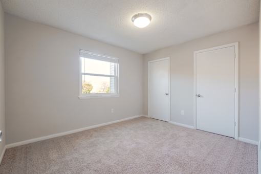 A room with a window and two doors.