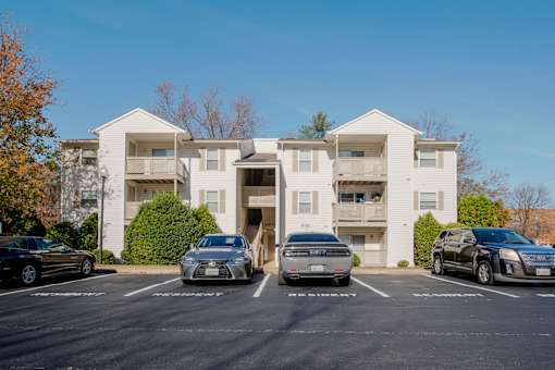 A white apartment building with cars parked in front.