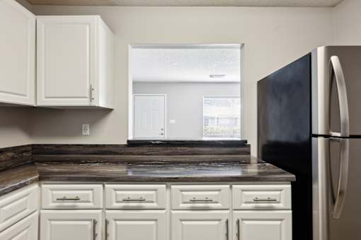 A kitchen with white cabinets and a black refrigerator.