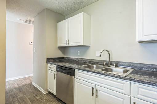 A kitchen with white cabinets and a black countertop.