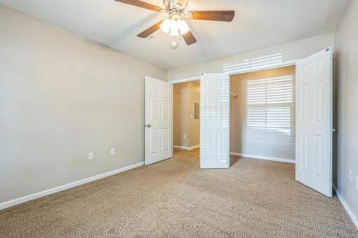 A room with a ceiling fan and carpeted floor.