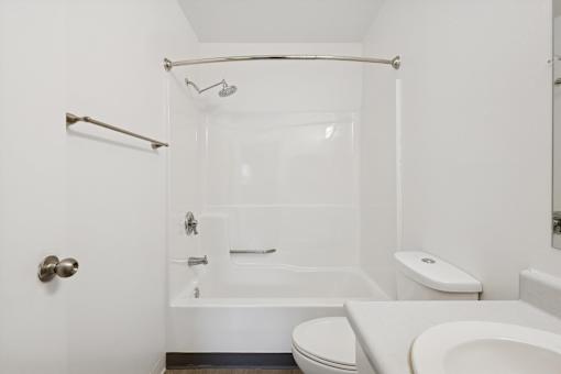 A white bathroom with a toilet, sink, and bathtub.