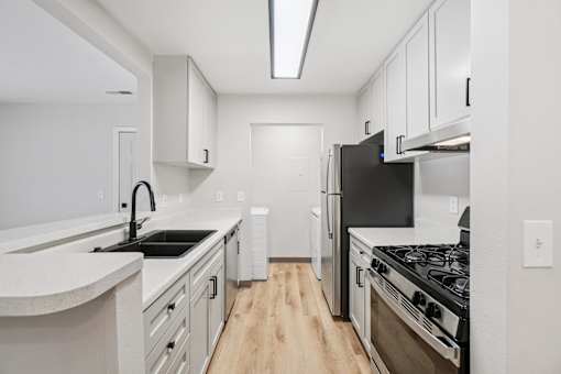A kitchen with black appliances and white cabinets.