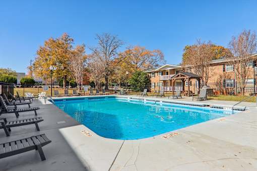 A swimming pool surrounded by trees and a building in the background.