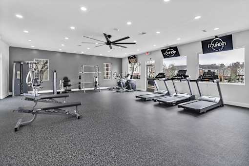 A gym with treadmills, weights, and a ceiling fan.