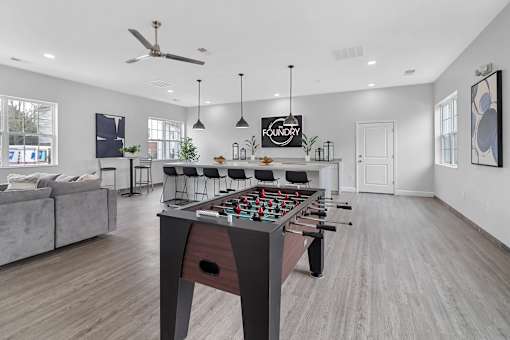 A foosball table is in the middle of a room with a couch and a fan.