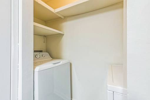A white washing machine is in a small laundry room.